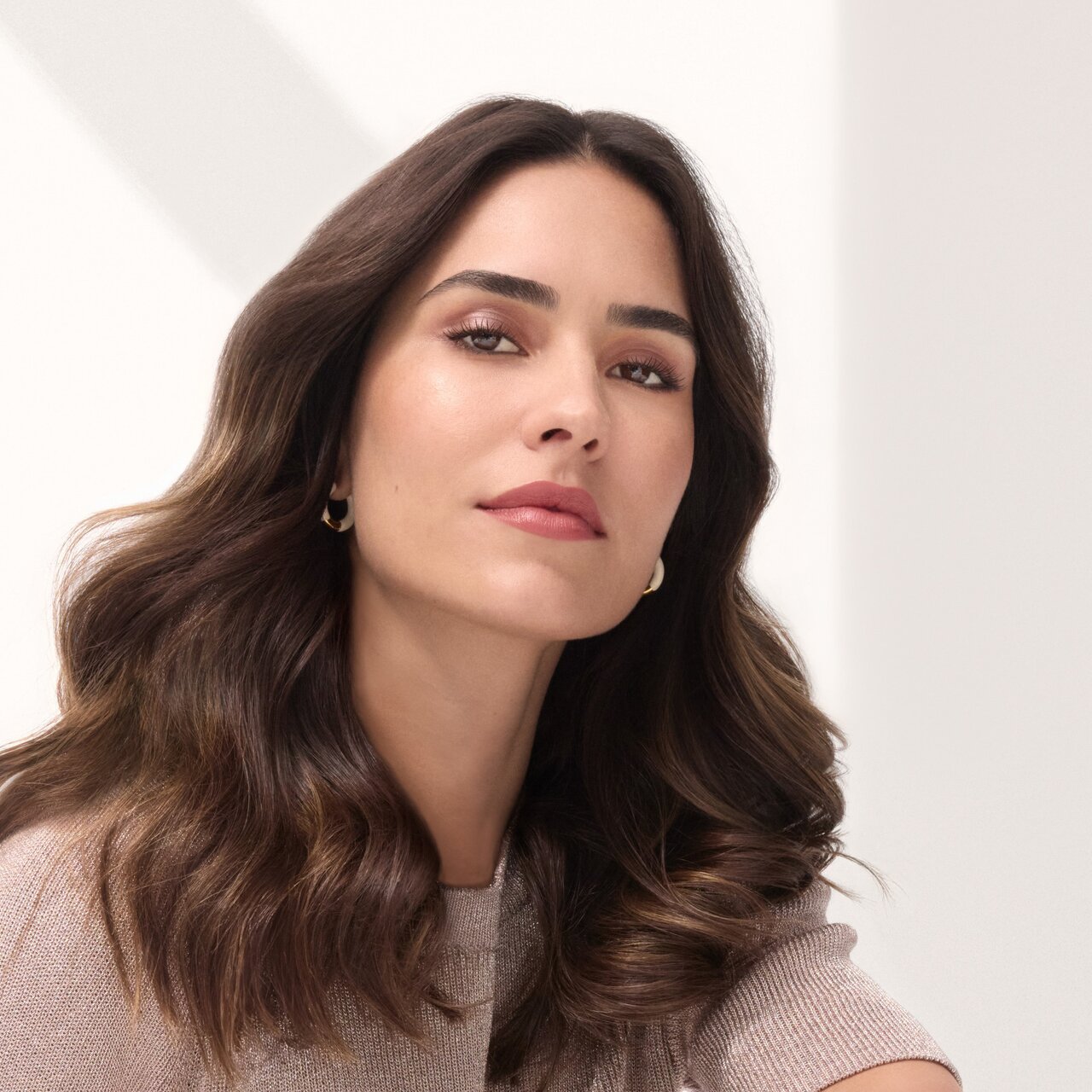 ALCINA Aktion ein rundes Make-up Schwämmchen gratis bei jeder Online Bestellung bis zum 05. September 2025. Junge Frau mit langen, voluminösen, braunen Haaren und sanften Wellen. Sie lächelt sanft in die Kamera.