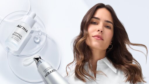 ALCINA Coffein Augenfluid und Booster Close-up des ALCINA Coffein Augenfluids sowie Coffein Boosters neben einer lächelnden jungen Frau mit leicht welligen braunen Haaren die offen über ihre Schulter fallen
