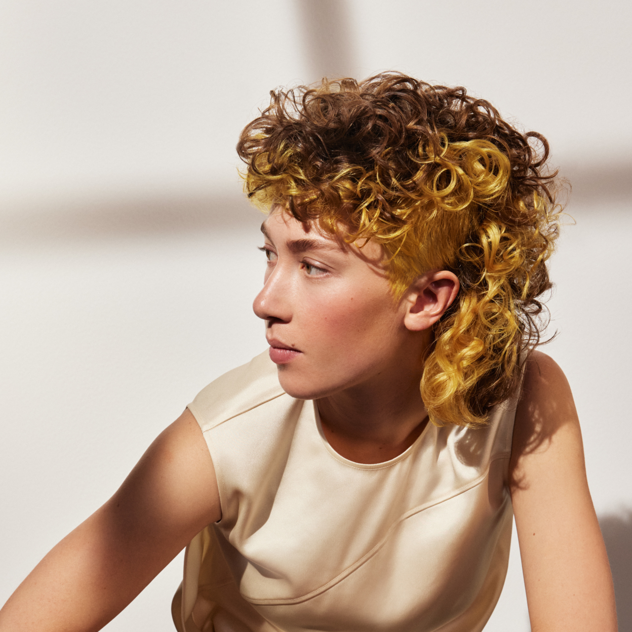 Porträt einer schönen jungen Frau mit einem Curly Mullet in der Trendhaarfarbe „Lemon Square“